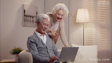 老年夫妇坐在沙发上使用<strong>笔记本电脑</strong>
